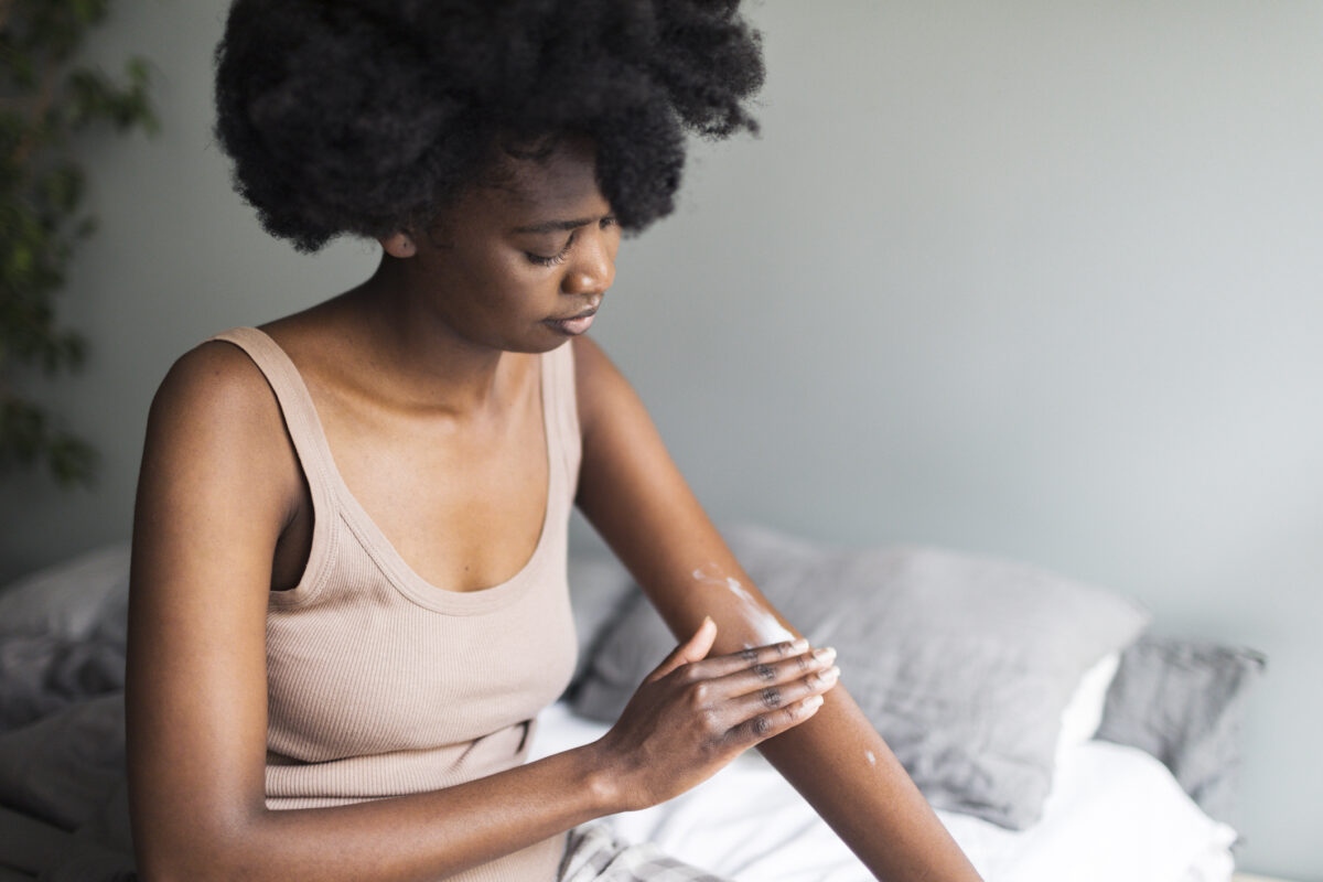 Young adult black woman applying skin cream at home in the morning